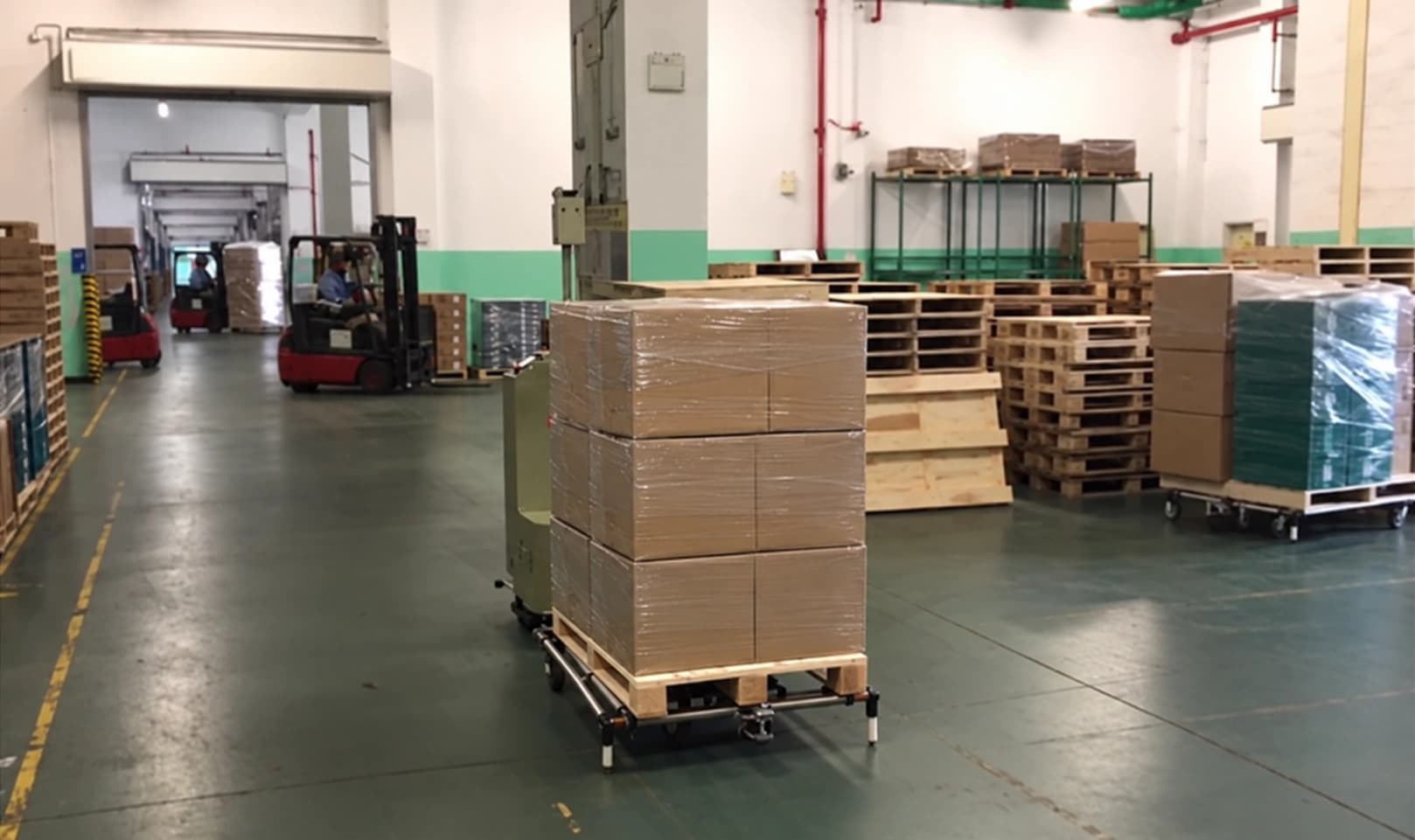 A tow AMR moving a pallet of cartons through a finished-goods area